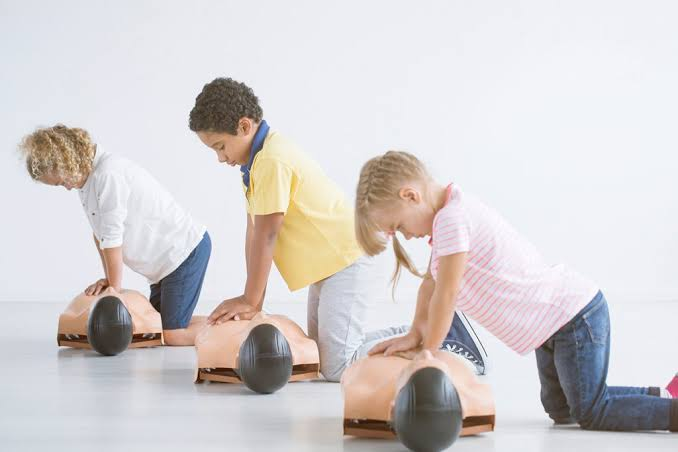 Niños practicando compresiones torácicas en maniquíes de entrenamiento