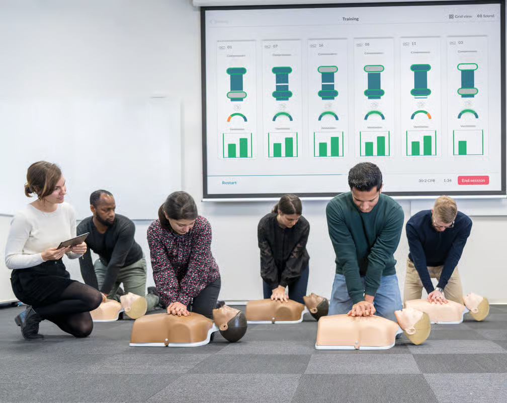 Adultos practicando reanimación con maniquíes de entrenamiento y retroalimentación digital